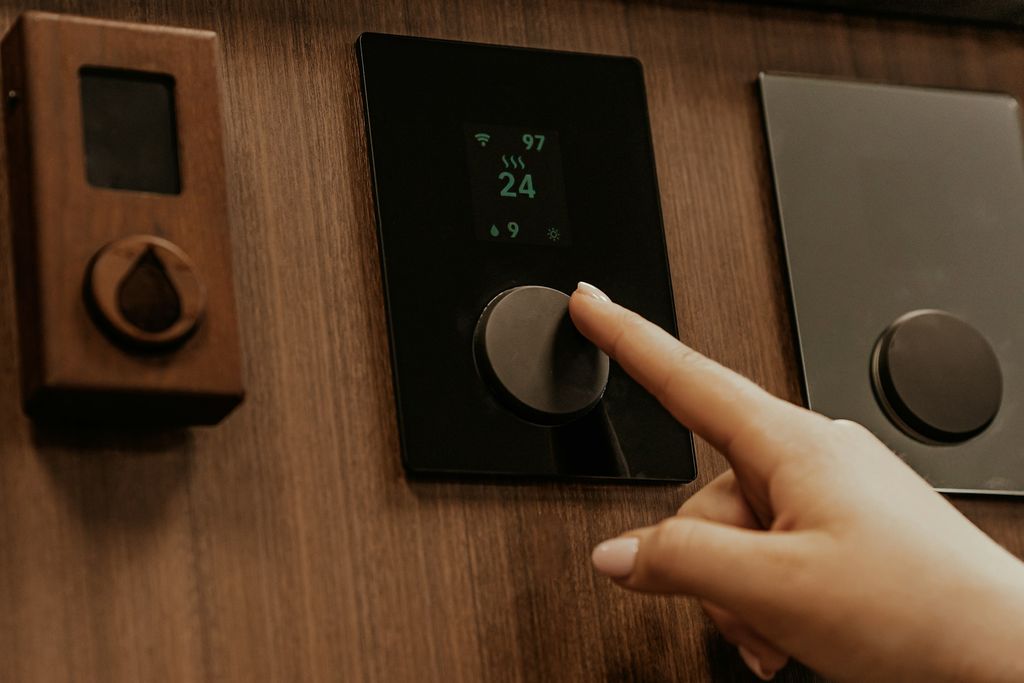 Mano che regola un termostato digitale a parete
